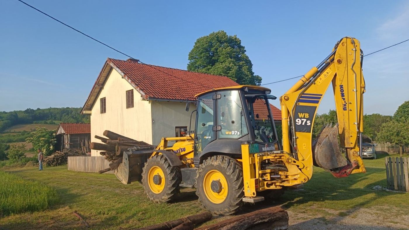 Komatsu WB97S kombinirka ispred kuće