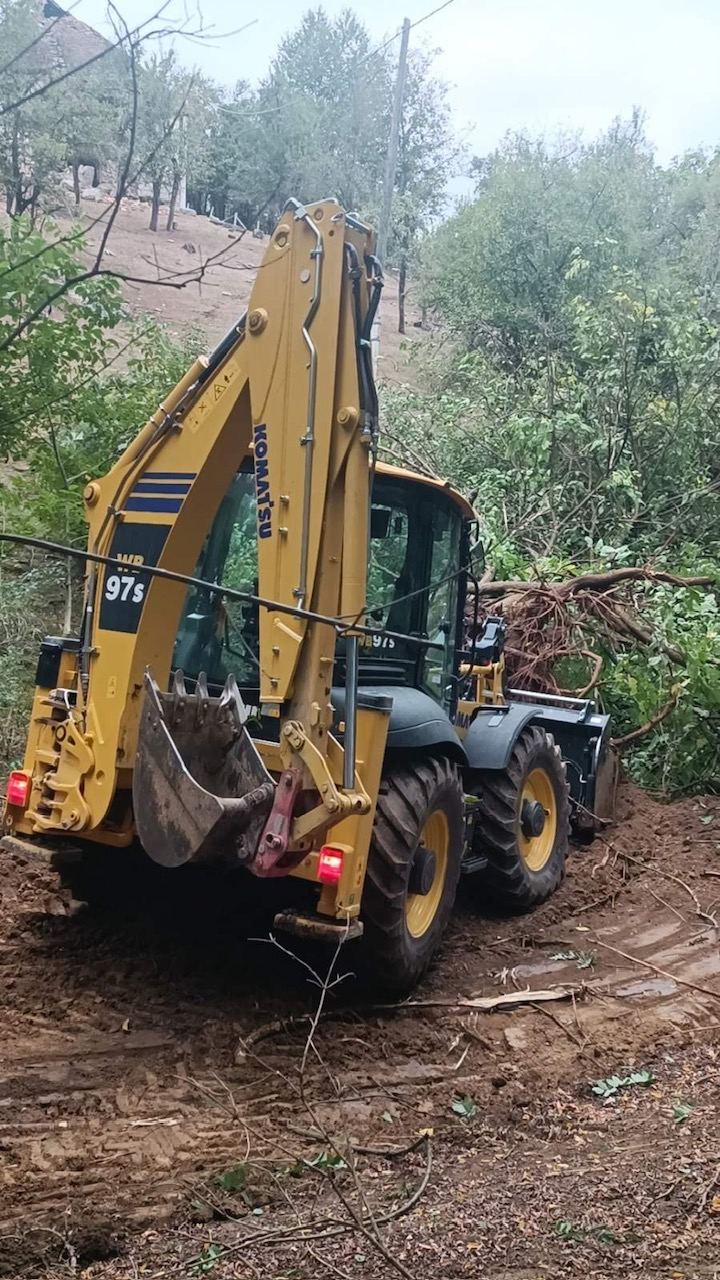 Komatsu WB97S kombinirka probija trasu kroz obraslu padinu